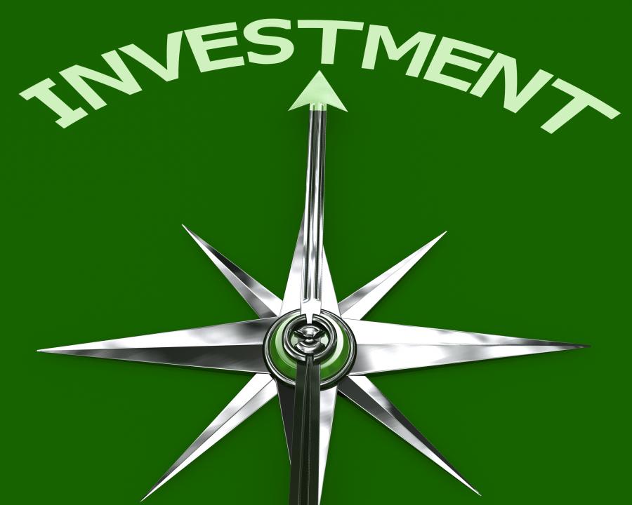 Compass arrow pointing to investment on green background stock photo Slide00