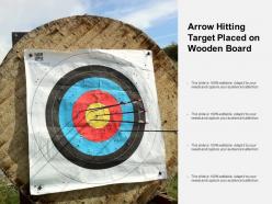 Arrow hitting target placed on wooden board