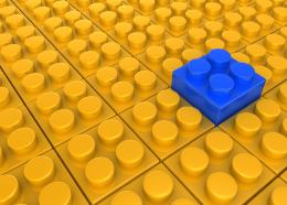 Blue lego block as leader on yellow lego block background stock photo
