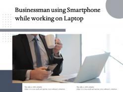 Businessman using smartphone while working on laptop