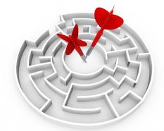 Circular maze with two red darts in center stock photo