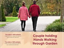Couple holding hands walking through garden