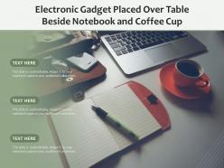 Electronic gadget placed over table beside notebook and coffee cup