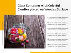 Glass container with colorful candies placed on wooden surface