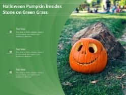 Halloween pumpkin besides stone on green grass