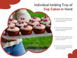 Individual holding tray of cup cakes in hand