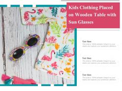 Kids clothing placed on wooden table with sun glasses