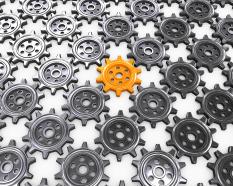 Multiple grey gears with one yellow gear as leader stock photo