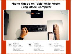 Phone placed on table while person using office computer
