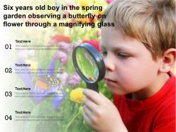 Six years old boy in the spring garden observing a butterfly on flower through a magnifying glass