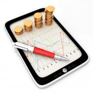 Tablet with line chart and stack of gold coins stock photo