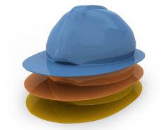 Three yellow orange blue engineering hats on white background stock photo