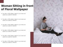 Woman sitting in front of floral wallpaper
