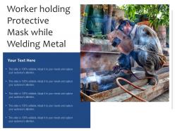 Worker holding protective mask while welding metal