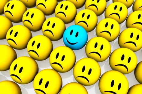 Blue happy face among yellow unhappy face icons stock photo