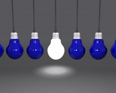 Hanging light bulbs with one glowing as leader stock photo