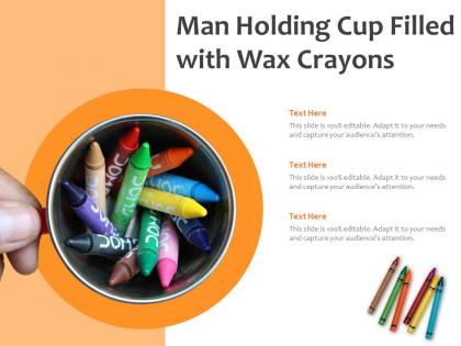 Man holding cup filled with wax crayons