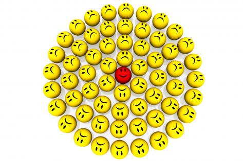 Multiple yellow sad emoticons with happy red one in center stock photo