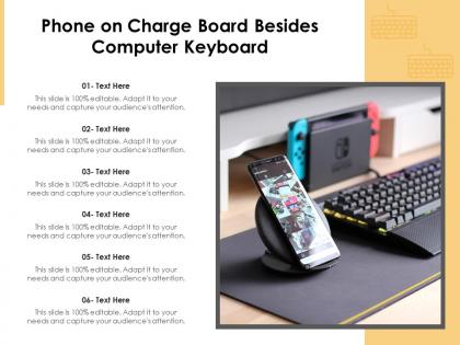 Phone on charge board besides computer keyboard