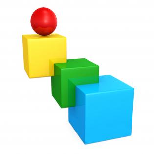 Three cubes in green blue yellow color with red ball on top as leader stock photo