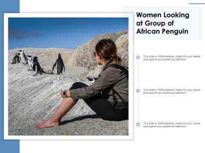 Women looking at group of african penguin
